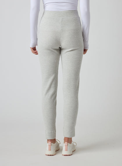 Women's Mavis Jogger in New Heather, back model view featuring a heather grey waffle-knit jogger with elasticated waistband, clean back panel, and tapered leg with cuffed hem paired with a white long sleeve top and white athletic shoes