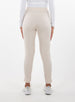 Women's Mavis Jogger in Oyster, back model view featuring an off-white waffle-knit jogger with elasticated waistband, clean back panel, and tapered leg with cuffed hem paired with a white long sleeve top and white athletic shoes