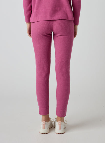 Women's Mavis Jogger in Rosewine, back model view featuring a bold rose waffle-knit jogger with elasticated waistband, clean back panel, and cuffed hem paired with a matching waffle-knit top and white athletic shoes