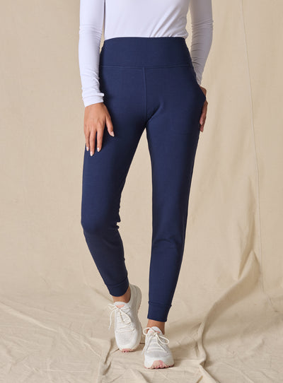 Women's Topia Jogger in New Indigo, front model view featuring a navy smooth-knit jogger with wide elasticated waistband and cuffed hem