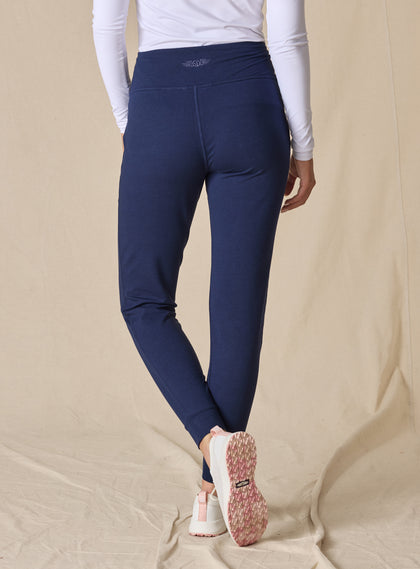 Women's Topia Jogger in New Indigo, back model view featuring a navy smooth-knit jogger with wide elasticated waistband and tonal Straight Down logo embroidery