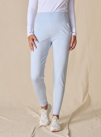 Women's Topia Jogger in Powder, front model view featuring a soft blue smooth-knit jogger with wide elasticated waistband and cuffed hem paired with a white long sleeve top and white athletic shoes