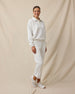 Woman wearing the Chelsea Pant in Coconut with a coordinating off-white long-sleeve top and white sneakers.