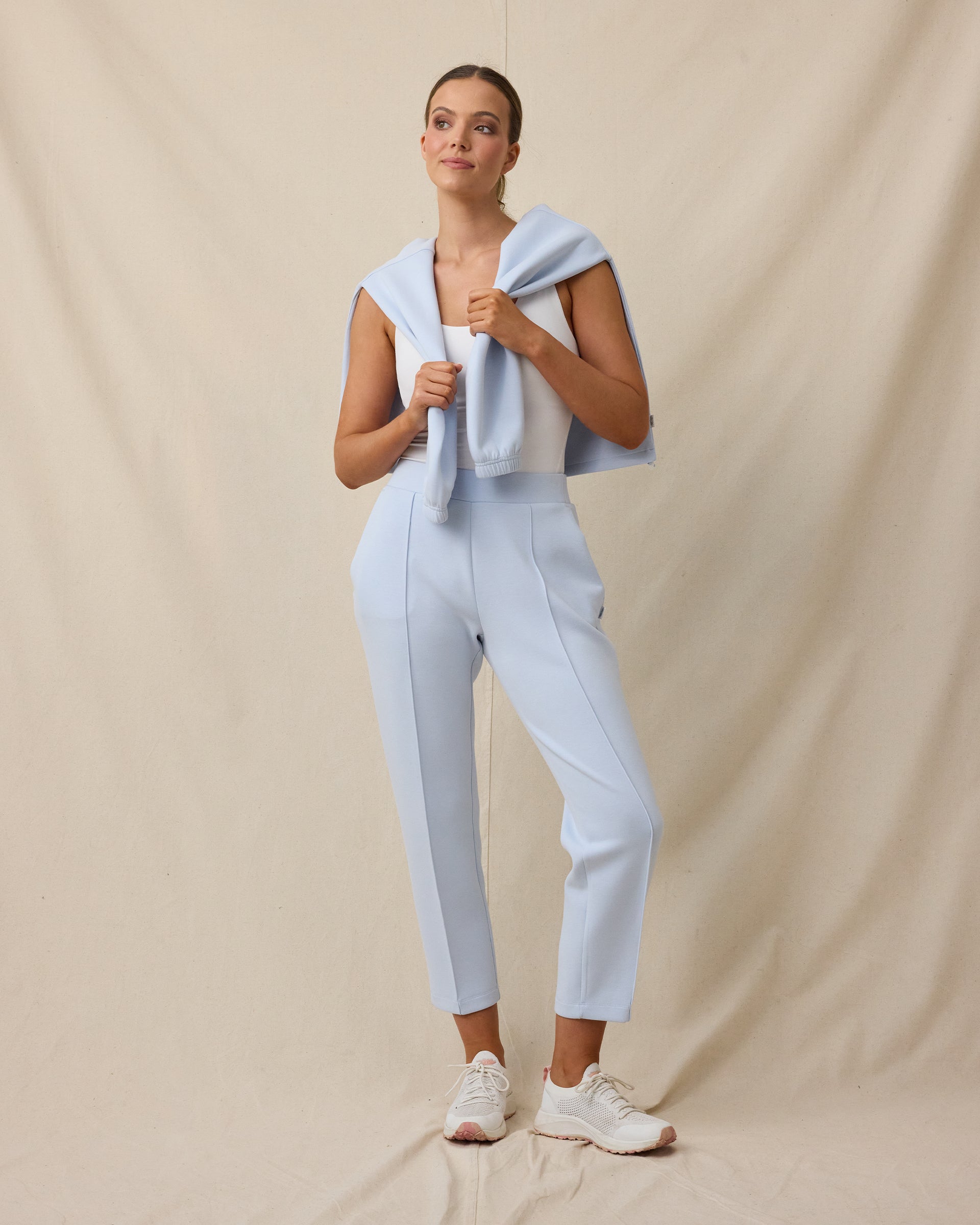 Woman wearing the Chelsea Pant in Lake with a white sleeveless top and coordinating layer draped over her shoulders.