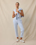 Woman wearing the Chelsea Pant in Lake with a white sleeveless top and coordinating layer draped over her shoulders.