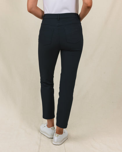 Women's Stride Pant in Black, back view on model featuring black ankle-length pants with two back pockets and Straight Down logo embroidery, paired with a white top and white golf shoes