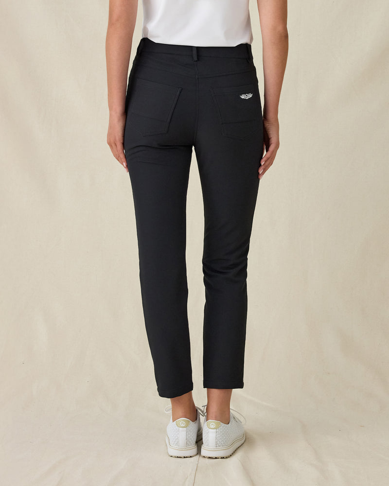 Women's Stride Pant in Black, back view on model featuring black ankle-length pants with two back pockets and Straight Down logo embroidery, paired with a white top and white golf shoes