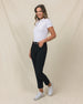 Women's Stride Pant in Black, full length side view on model featuring black ankle-length pants with high rise waist and gold button closure, paired with a white polo and white golf shoes