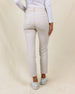 Women's Stride Pant in Stone, back view on model featuring a stone colored ankle pant with two back patch pockets and Straight Down logo, paired with a white long sleeve polo and white golf shoes