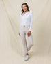 Women's Stride Pant in Stone, full length front view on model featuring a stone colored ankle pant with front patch pockets, paired with a white long sleeve polo and white golf shoes