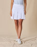 Women's Martina Skort in White, front view on model featuring a white pleated skort with a wide waistband paired with a light blue sleeveless top and white golf shoes