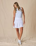 Women's Martina Skort in White, full front view on model featuring a white pleated skort with a wide waistband paired with a light blue sleeveless top and white golf shoes