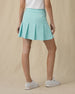 Women's Martina Skort in Green Stone, back on-model view from the waist down featuring a solid mint green pleated skort with a wide waistband and Straight Down logo embroidered at the back waistband, paired with a white top and white shoes