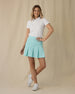 Women's Martina Skort in Green Stone, full-length front on-model view with hand on hip featuring a solid mint green pleated skort with a wide waistband, paired with a white short sleeve polo and white shoes