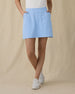 Evie Skort in Carolina, front view on model showing a light blue skort with front patch pockets, paired with a white polo and white golf shoes