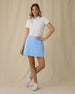 Evie Skort in Carolina, full length front view on model showing a light blue skort with front patch pockets, paired with a white polo and white golf shoes