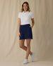 Evie Skort in New Indigo, full length front view on model showing a navy skort with front patch pockets, paired with a white polo and white golf shoes