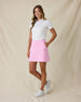 Evie Skort in Pink Floyd, full-length side-angle view on model in solid pink with front pockets, paired with a white polo and white golf shoes