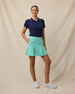 Korra Skort in Cascade Green paired with a navy polo and white golf shoes, full outfit model view