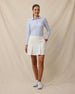 Model wearing the Korra Skort in Coconut paired with a light blue long-sleeve polo