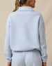A woman modeling from the back wearing a light blue cropped long-sleeve top and matching light blue bottoms.