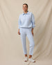 A woman modeling a light blue long-sleeve polo sweatshirt and matching light blue cropped pants, paired with white sneakers.
