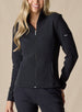 Swing Jacket in Black, front view on model featuring solid black fabric with subtle horizontal texture, full zip closure, and stand collar styled with black pants