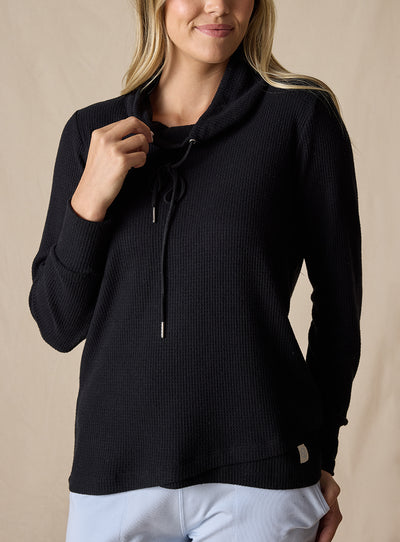 Women's Misty Top in Black, front view on model featuring a solid black waffle knit long sleeve top with cowl neck and drawstring tie