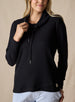 Women's Misty Top in Black, front view on model featuring a solid black waffle knit long sleeve top with cowl neck and drawstring tie