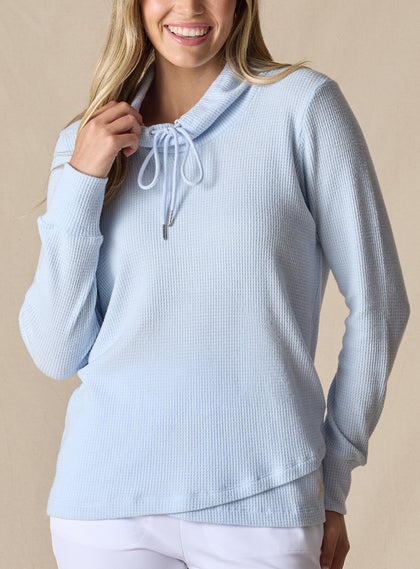 Women's Misty Top in Lake, front view on model featuring a solid light blue waffle knit long sleeve top with cowl neck and drawstring tie