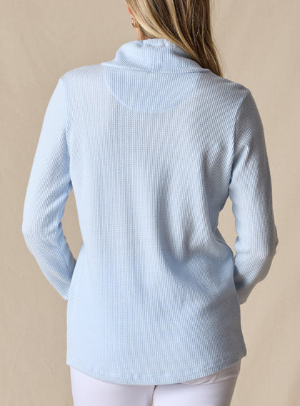 Women's Misty Top in Lake, back view on model featuring a solid light blue waffle knit long sleeve top with cowl neck