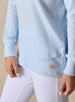 Women's Misty Top in Lake, close detailed view featuring a solid light blue waffle knit long sleeve top with crossover hem and Straight Down patch, paired with white pants