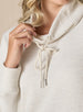 Women's Misty Top in Oatmeal, detailed close-up view on model featuring a cream waffle knit long sleeve top with cowl neck and drawstring tie