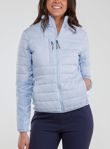 Straight Down Women's Pines Jacket in Powder, front model view showing light blue quilted body with stand collar, chest zip pocket, and full zip closure paired with navy pants