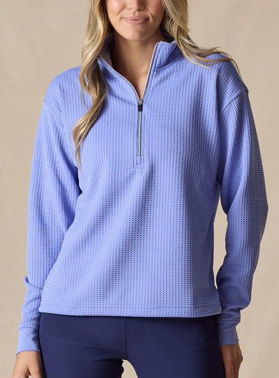 Women's Opal Half Zip in Bluebell, front view on model featuring a medium blue waffle-textured pullover with a quarter-zip neckline paired with navy pants