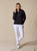 Women's Opal Half Zip in Black, full front view on model featuring a black waffle-textured pullover with a quarter-zip neckline paired with white pants and white golf shoes