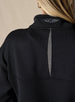 Women's Opal Half Zip in Black, close-up back detail view featuring the waffle-texture fabric, charcoal center back vent, and embroidered logo at the collar