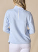 Women's Opal Half Zip in Powder, back view on model featuring a light blue waffle-textured pullover with an embroidered Straight Down logo at the collar and a white center back vent detail paired with white pants