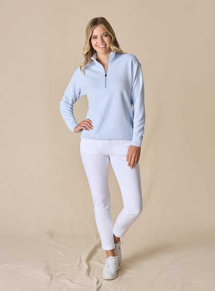 Women's Opal Half Zip in Powder, full front view on model featuring a light blue waffle-textured pullover with a quarter-zip neckline paired with white pants and white golf shoes