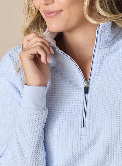 Women's Opal Half Zip in Powder, close-up front detail view featuring the waffle-texture fabric, contrast striped zipper, white collar lining, and ribbed cuffs