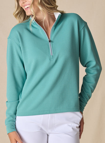 Women's Opal Half Zip in Sea Green, front view on model featuring a sea green waffle-textured pullover with a quarter-zip neckline and contrast striped zipper paired with white pants