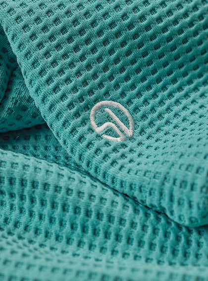Women's Opal Half Zip in Sea Green, close-up detail view featuring the waffle-texture fabric and embroidered Straight Down logo at the hem
