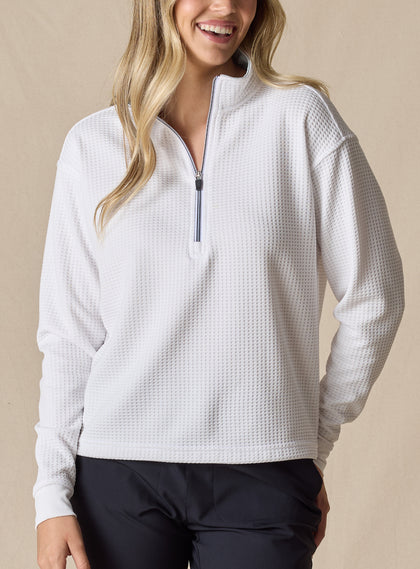 Women's Opal Half Zip in White, front view on model featuring a white waffle-textured pullover with a quarter-zip neckline and contrast navy zipper paired with black pants