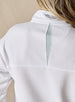 Women's Opal Half Zip in White, close-up back detail view featuring the waffle-texture fabric, sage green center back vent, and embroidered logo at the collar