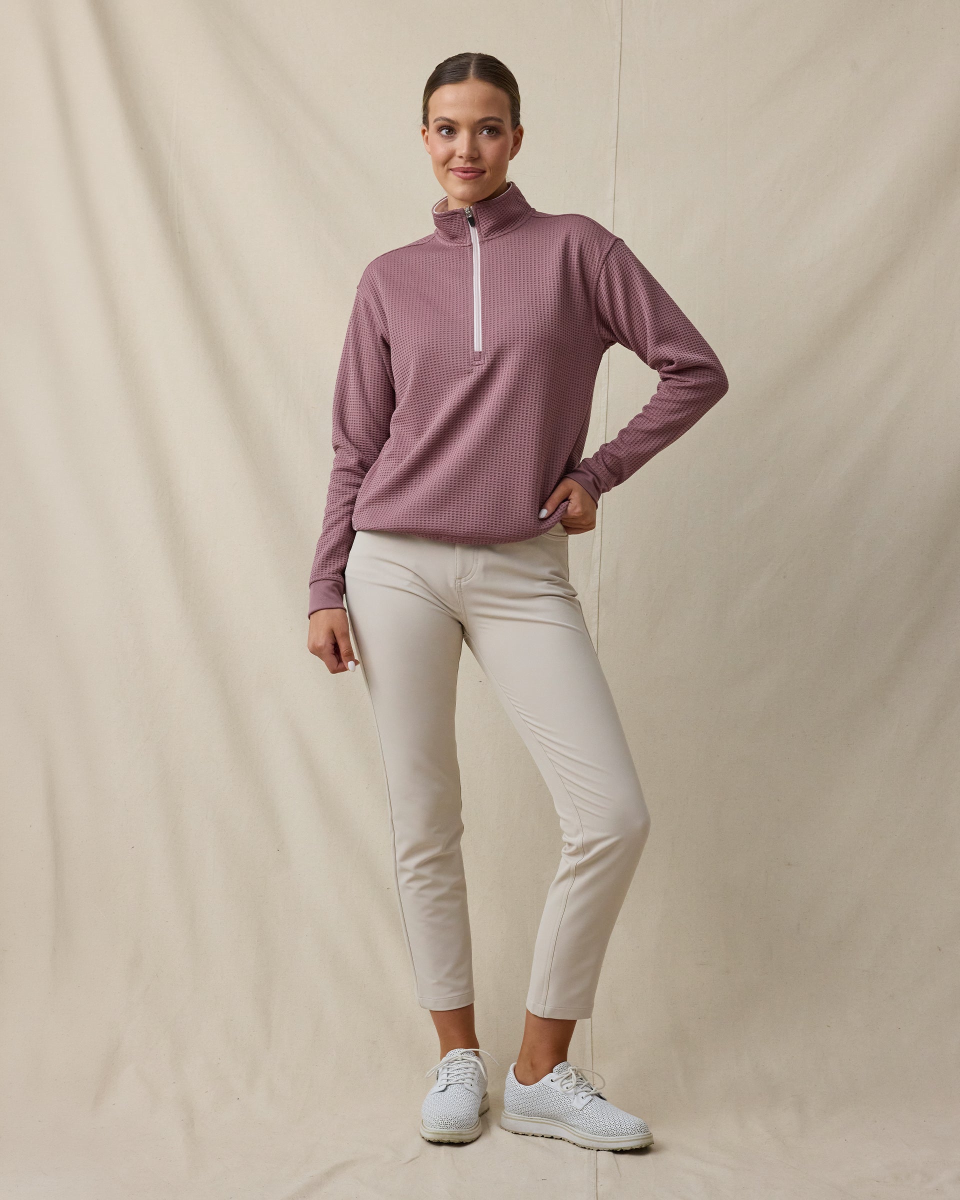 Woman wearing the Straight Down Opal Half Zip in Oxblood Red with a contrast half-zip mock neck and light golf pants