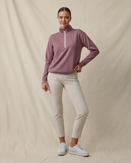 Woman wearing the Straight Down Opal Half Zip in Oxblood Red with a contrast half-zip mock neck and light golf pants