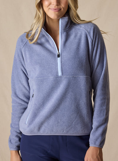 Cerro Quarter Zip in Bluestone, front on-model view featuring a solid blue-grey fleece quarter-zip pullover with a stand-up collar, light blue contrast zipper, and zippered hand pockets, styled with navy pants