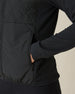Women's Hera Jacket in Black, close-up detail view featuring the zippered side pocket with model's hand inserted, showcasing the contrast between the quilted front body and solid knit sleeve