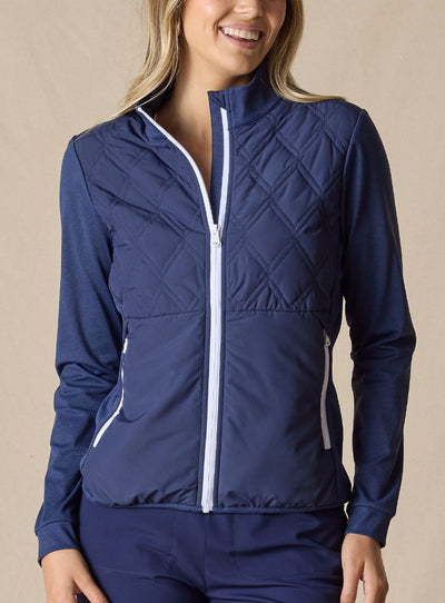 Women's Hera Jacket in New Indigo, front view on model featuring a diamond quilted front body with solid navy knit sleeves, full-zip stand collar with white zipper and trim detail, and white zippered side pocket, paired with matching navy pants
