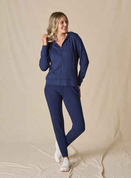 Women's Mesa Hooded Jacket in New Indigo, full length model view featuring a navy full-zip hoodie with drawstring hood paired with matching pants and white athletic shoes